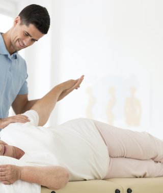Fizjoterapeuta instruuje starszą pacjentkę w ćwiczeniu